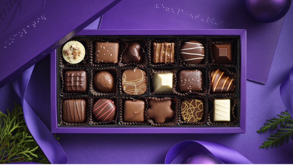 A box of assorted Purdy’s chocolates in purple packaging with braille on the lid.